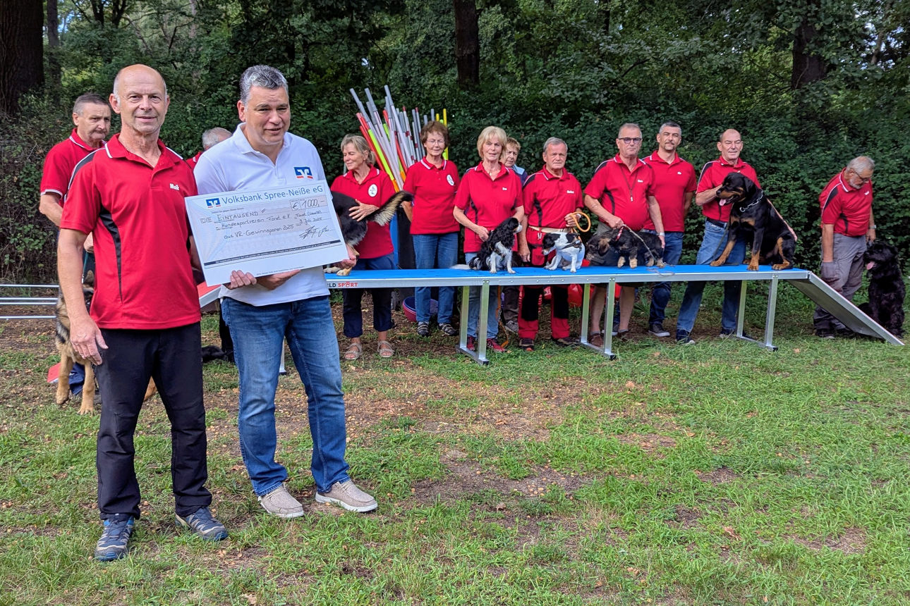Vereinsmitglieder mit ihren Hunden und Laufsteg im Hintergrund