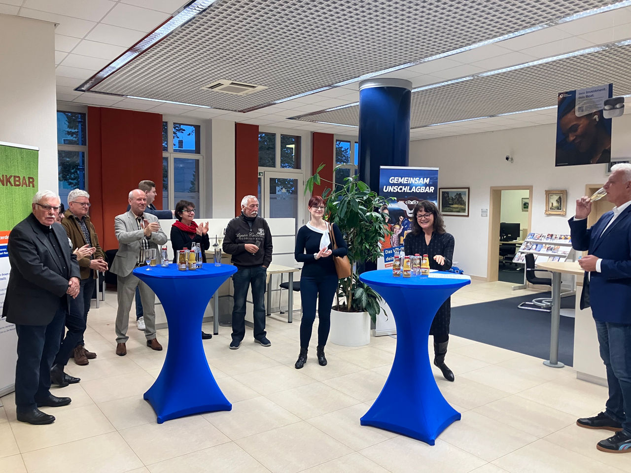 Eine Gruppe steht gemeinsam in einer Bankfiliale