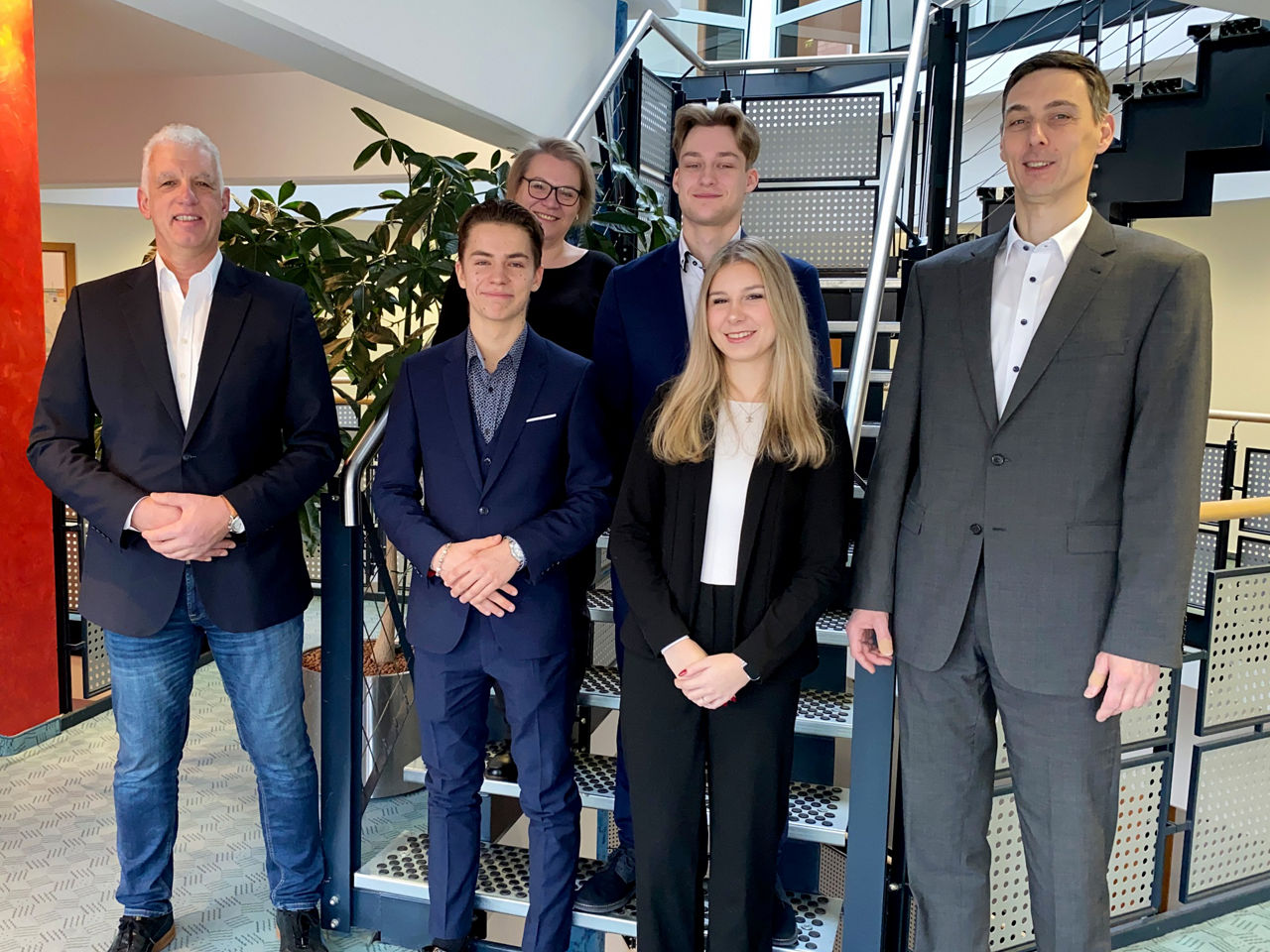Frauen und Männer stehen vor einer Treppe