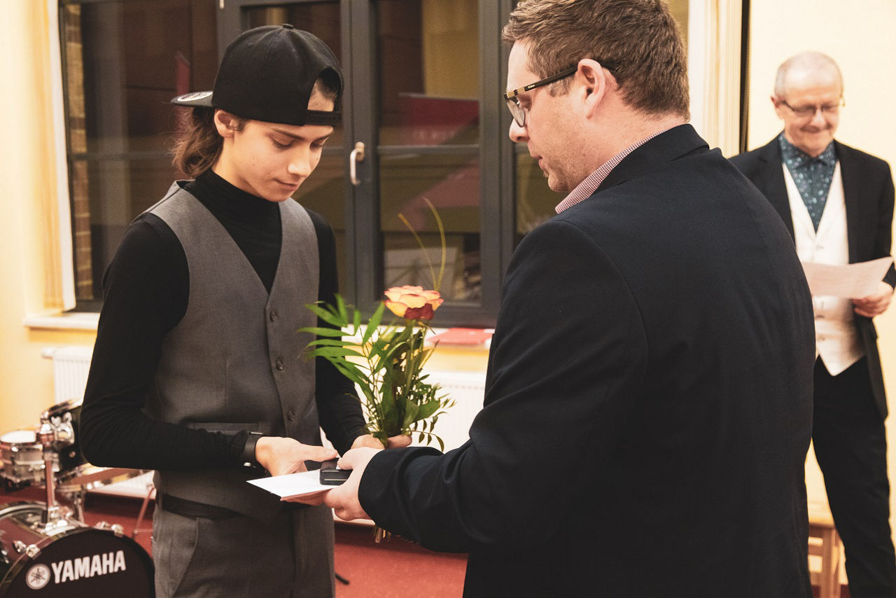 Mann überreicht einem jungen Menschen ein Geschenk