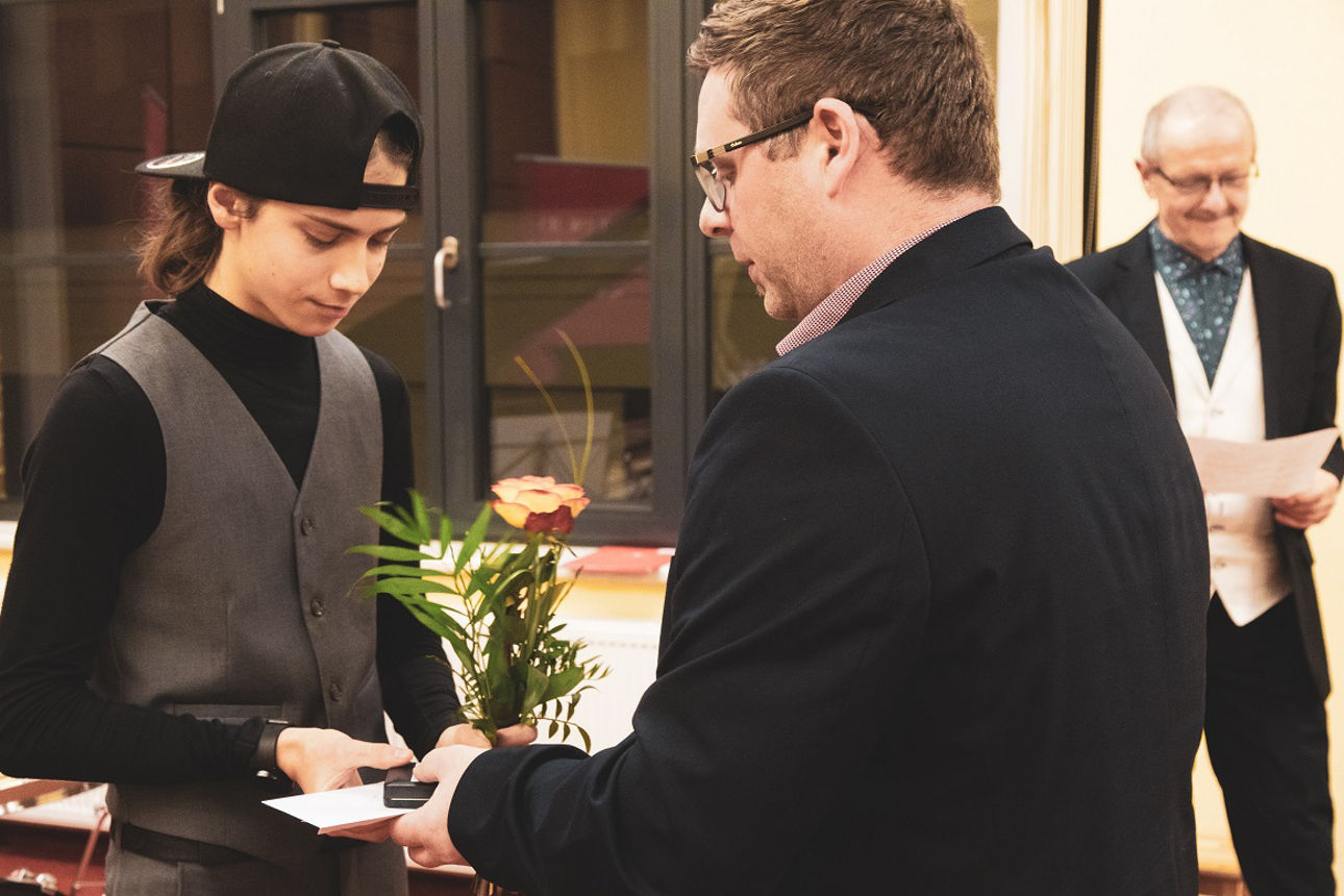 Mann übergibt einem jungen Menschen ein Geschenk