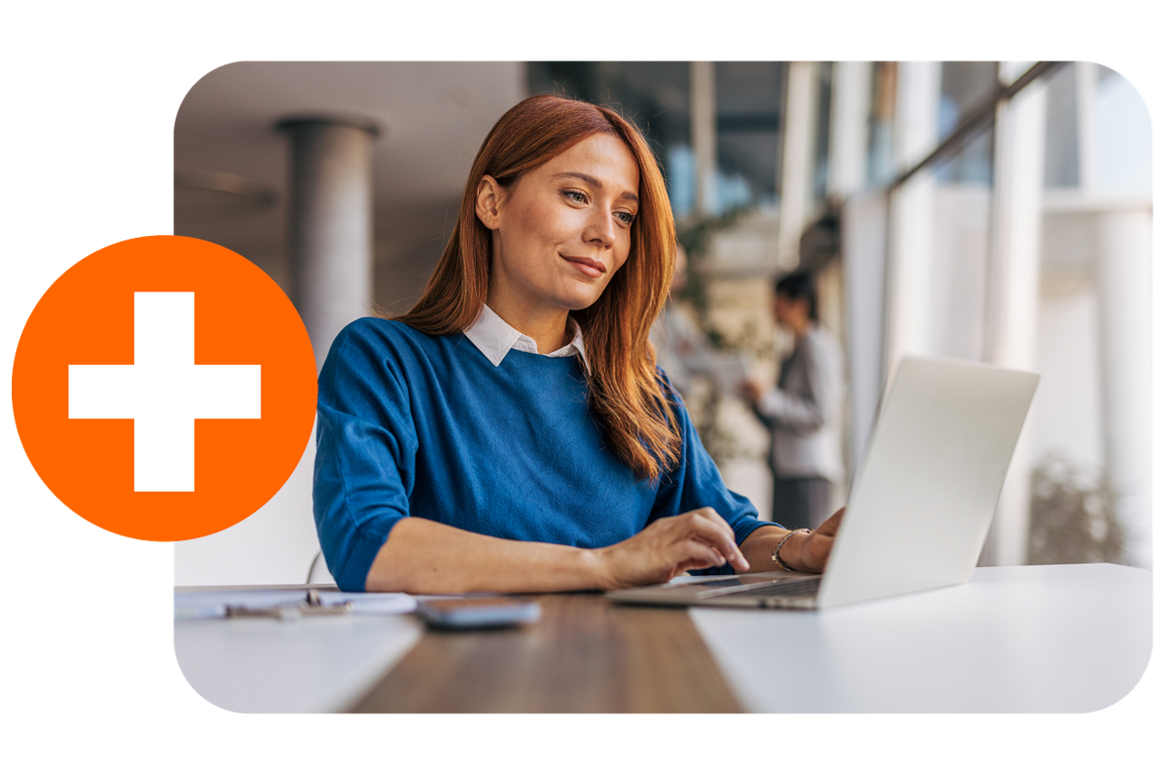 Frau im blauen Pulli sitzt lächelnd vor Laptop