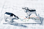 Zwei Silberfiguren (Bär und Bulle) stehen auf einem Aktienkurs-Chart