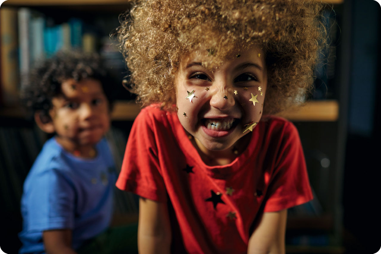 Zwei Kinder mit Sternen im Gesicht lachen in die Kamera