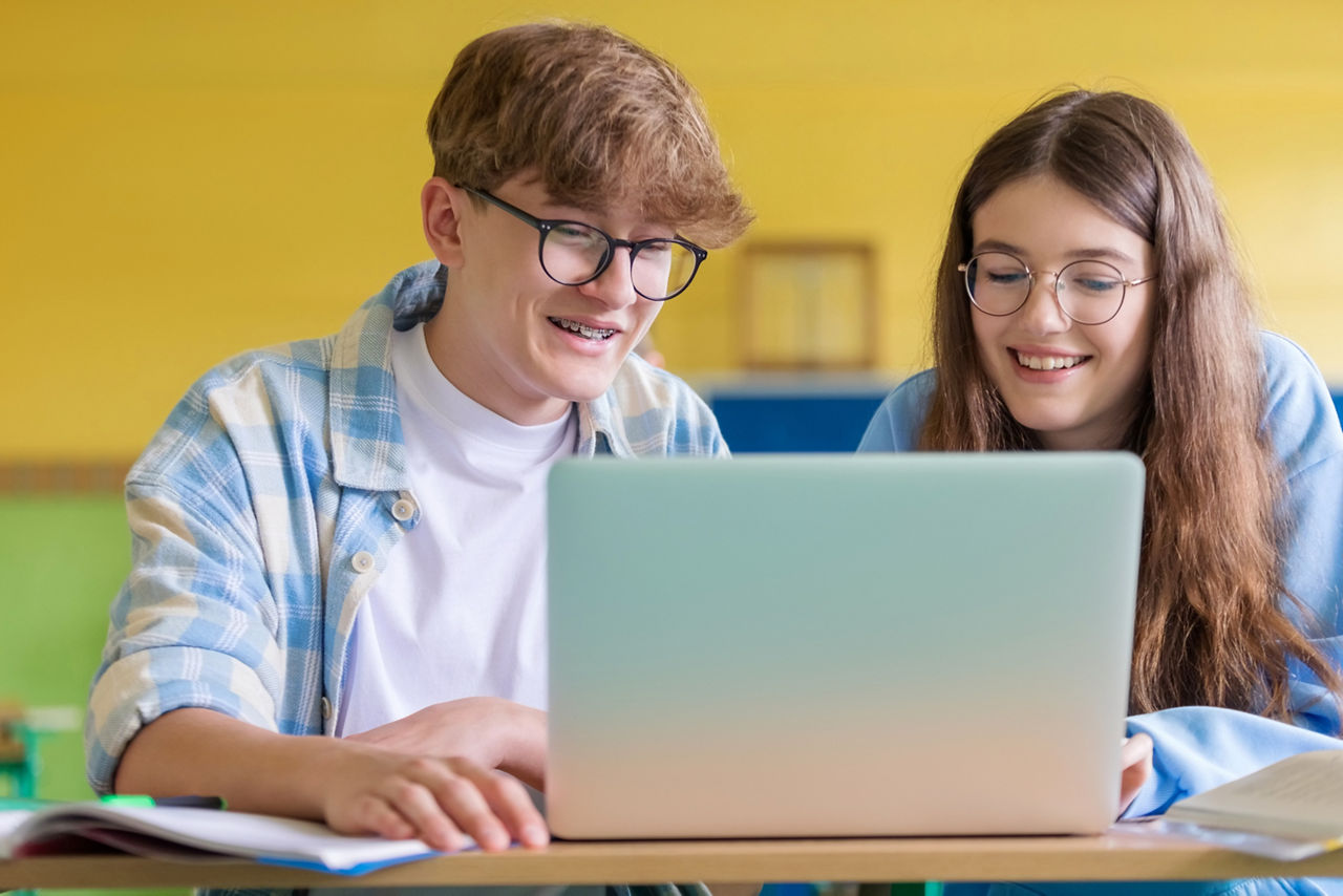 Junge und Mädchen sitzen gespannt vor dem Laptop 