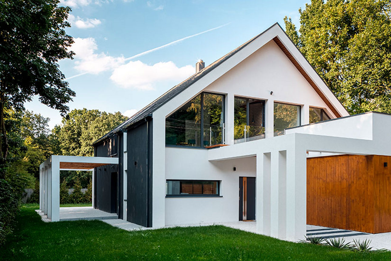 Eine Frau mit blonden Haaren sitzt am Küchentisch mit einer Tasse Kaffee in der Hand und lächelt einen Hund an