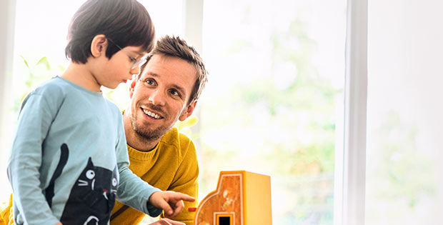 Junge und Vater spielen zusammen mit einer kleinen Registrierkasse