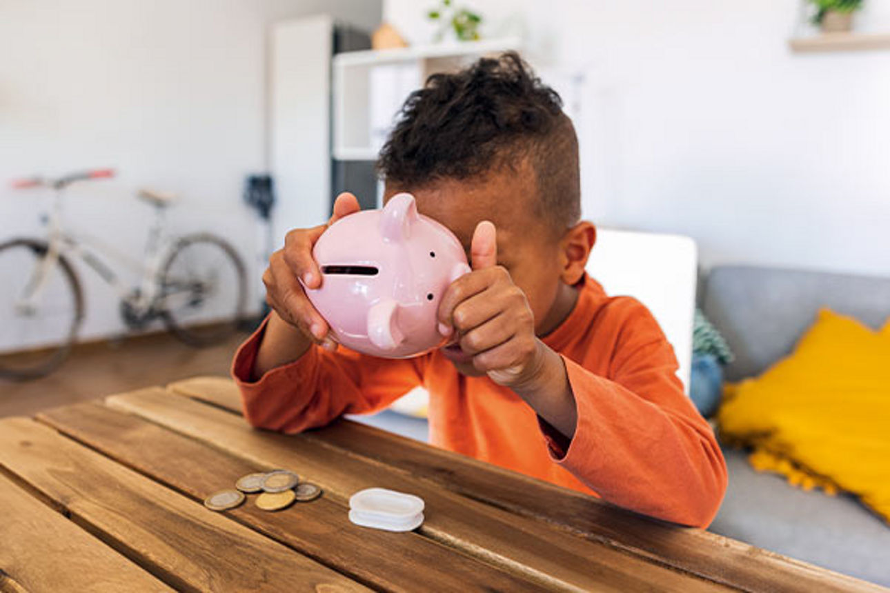 Ein Junge schüttelt ein Sparschwein.