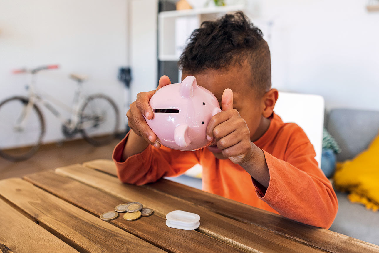 Kleiner Junge kippt rosa Sparschwein aus