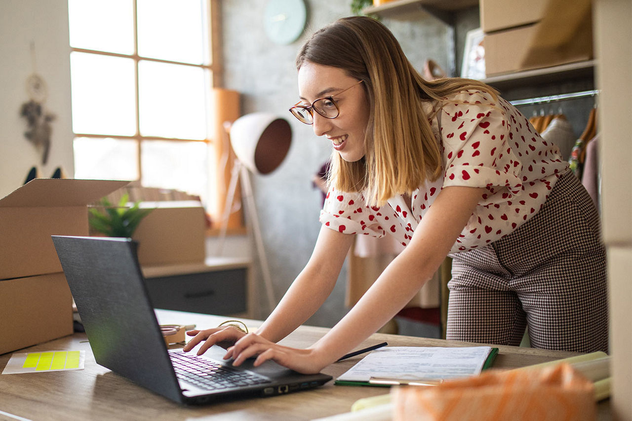 junge frau steht in ihrem wohnzimmer und betreibt ihren online shop
