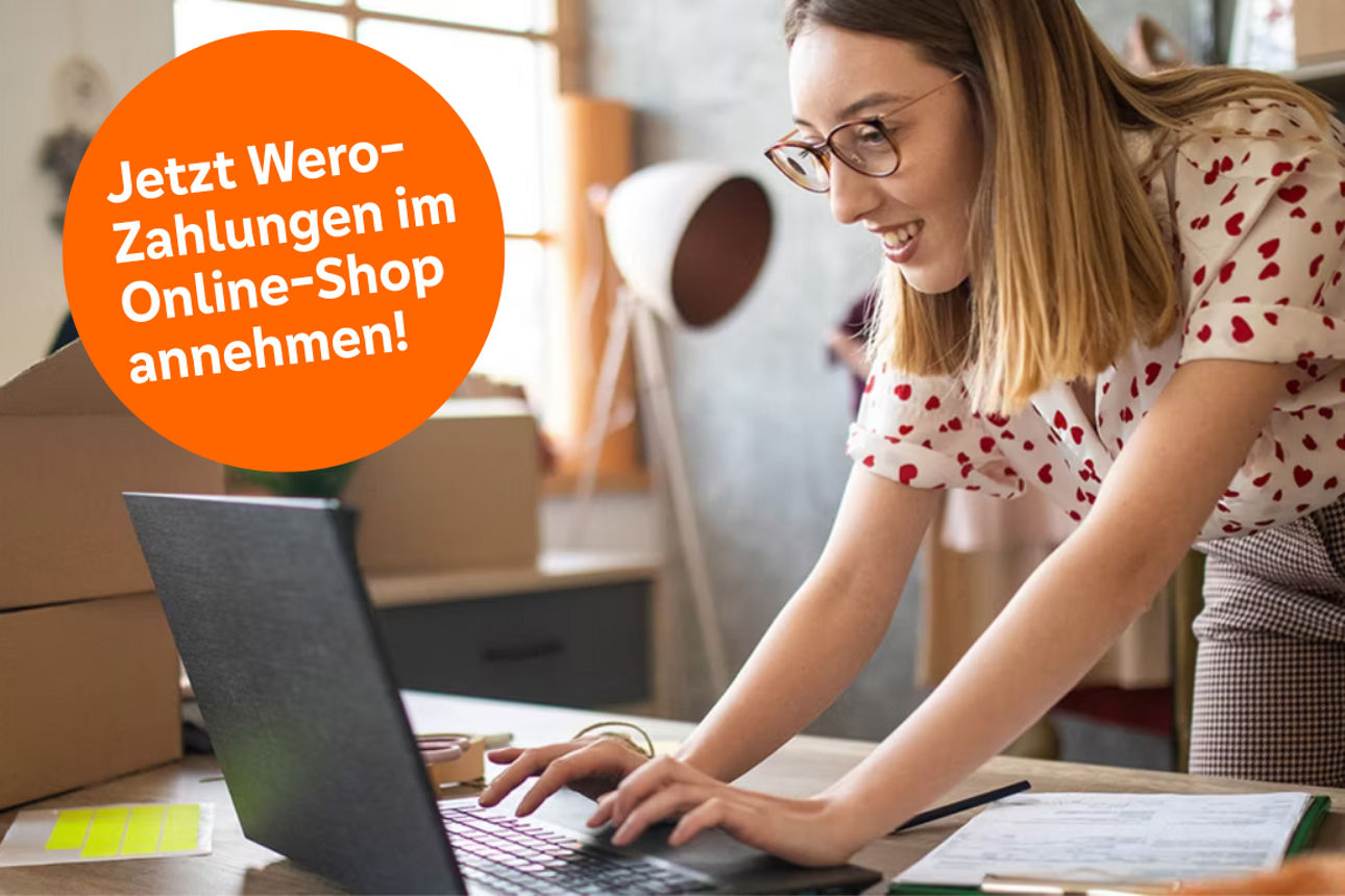 Person packt Versandkartons am Schreibtisch, arbeitet am Laptop und wirbt für Wero‑Zahlungen im Online‑Shop.