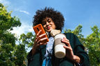 outdoor & von unten abgelichtete Frau mit Handy und Kaffee in der Hand 