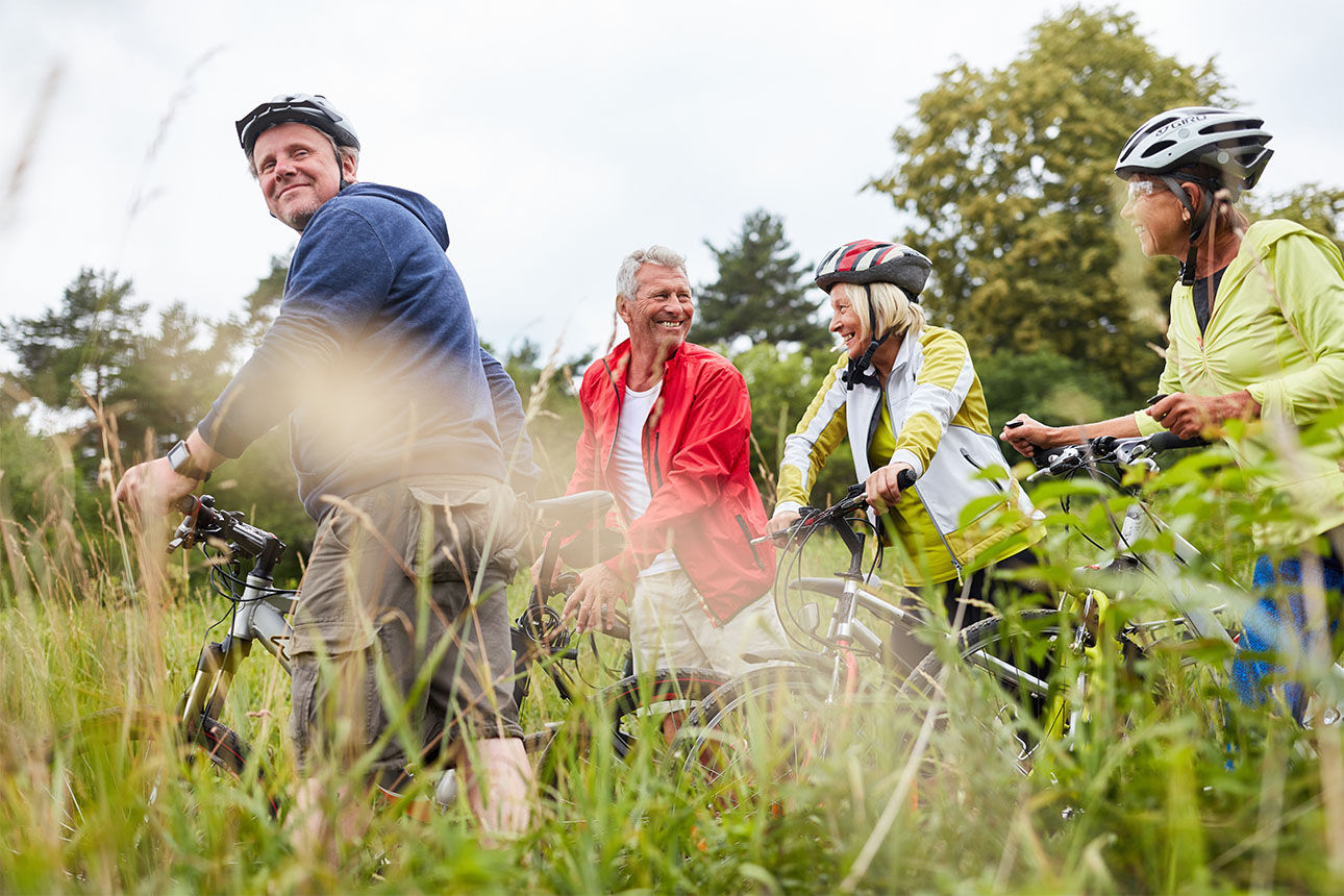 Gruppe von Fahrrad-Fahren lächelnd in der Natur unterwegs.