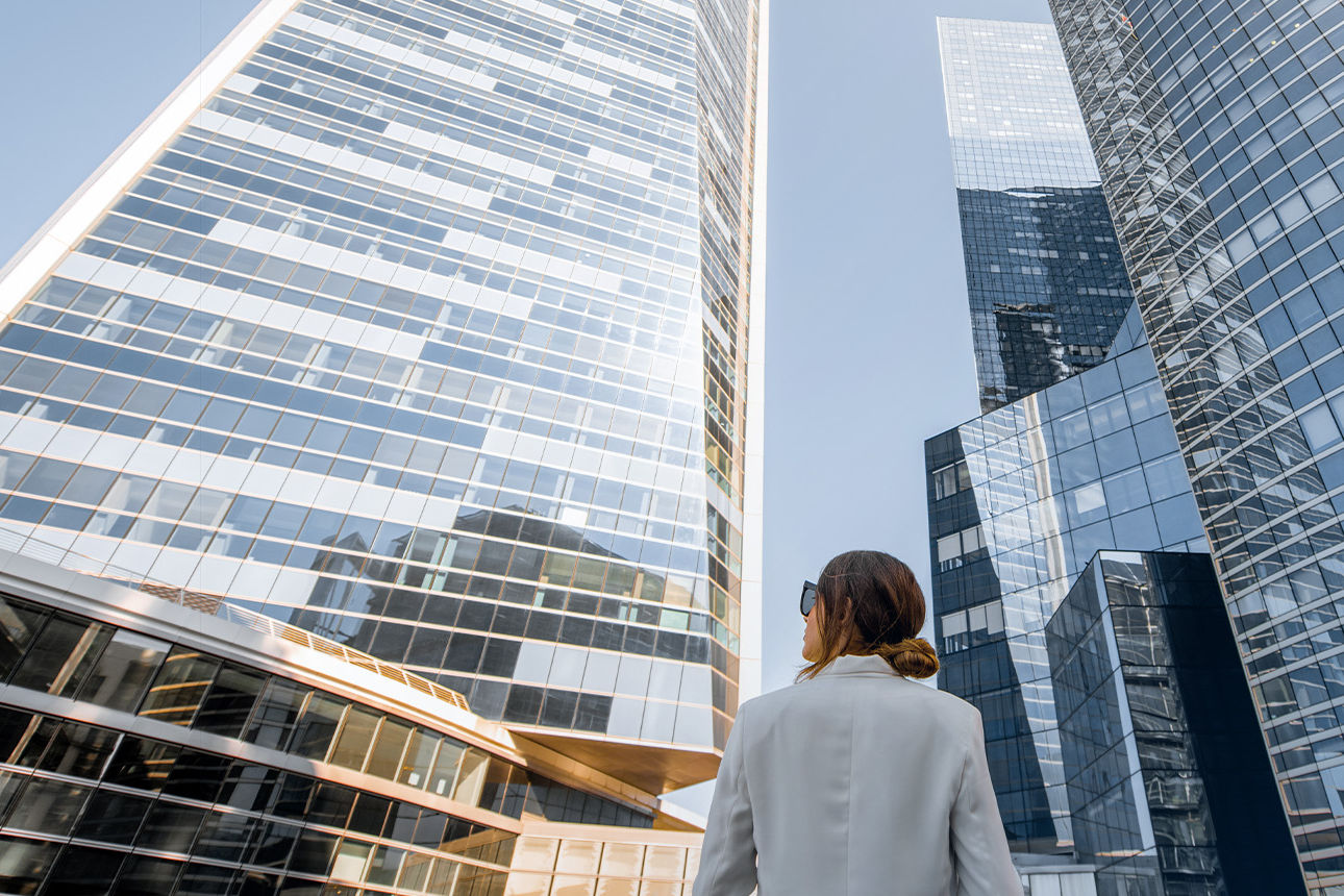 Junge Frau blickt zu Hochhäusern herauf