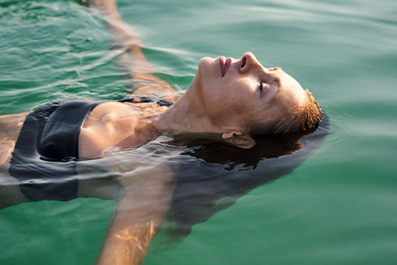 Junge Frau treibt entspannt auf dem Wasser