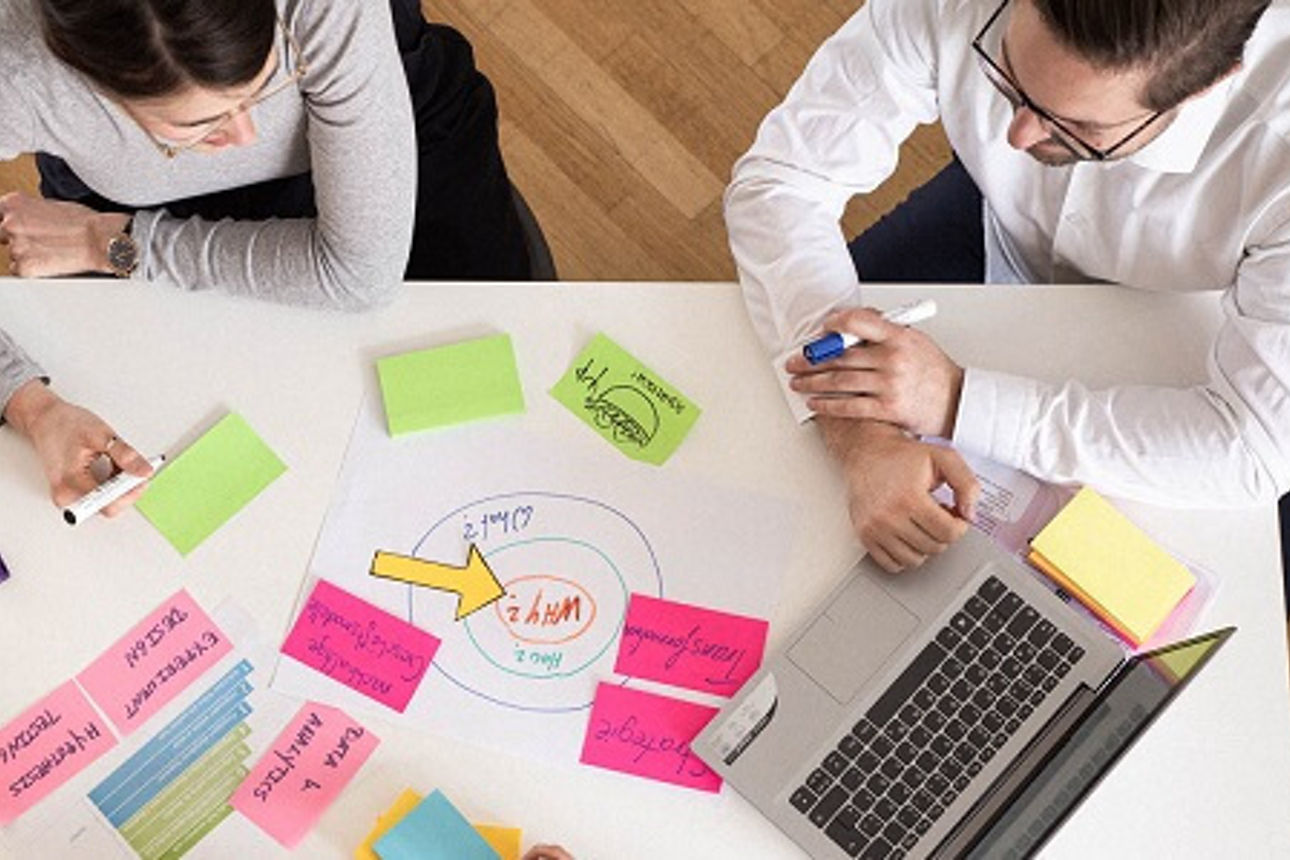 Zwei Personen sitzen am Tisch und erarbeiten eine Strategie mit Klebezetteln