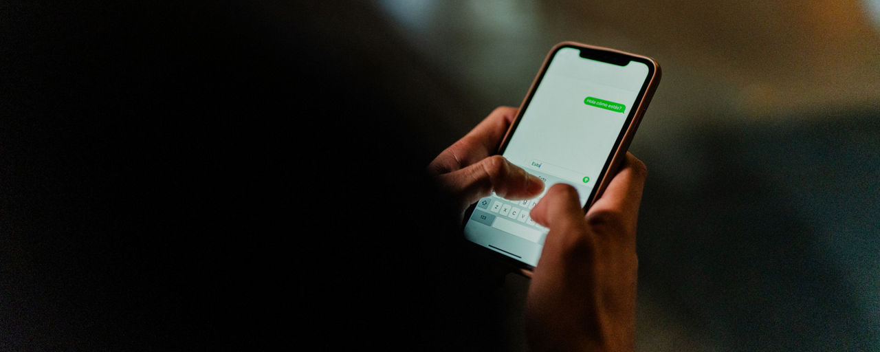 Männerhände tippen auf Smartphone im Dunklen