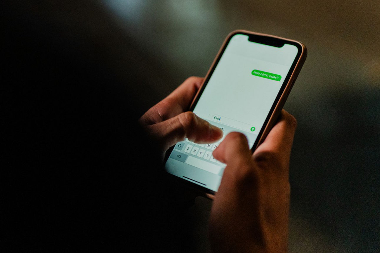 Männerhände tippen auf Smartphone im Dunklen