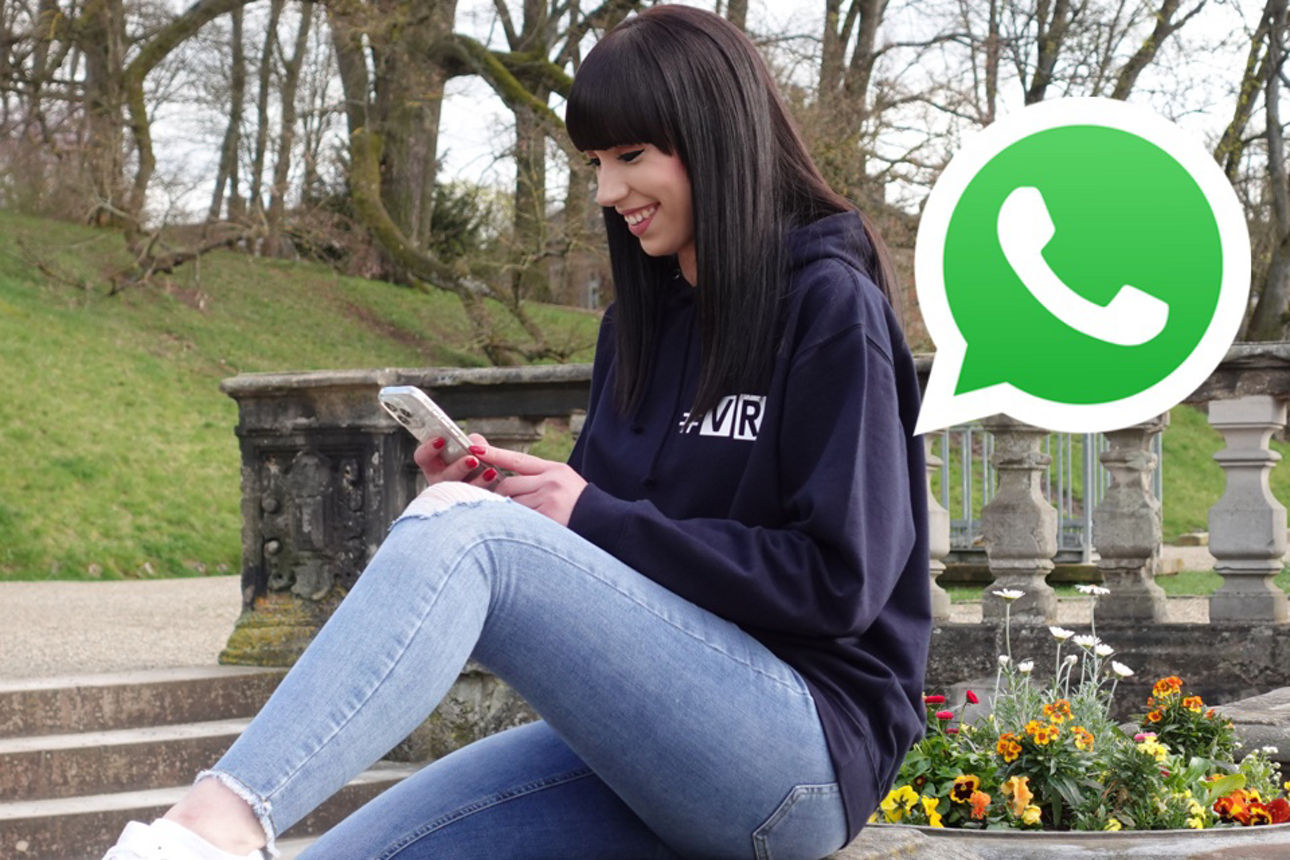 Eine junge Frau sitzt mit dem Smartphone auf einer Ballustrade