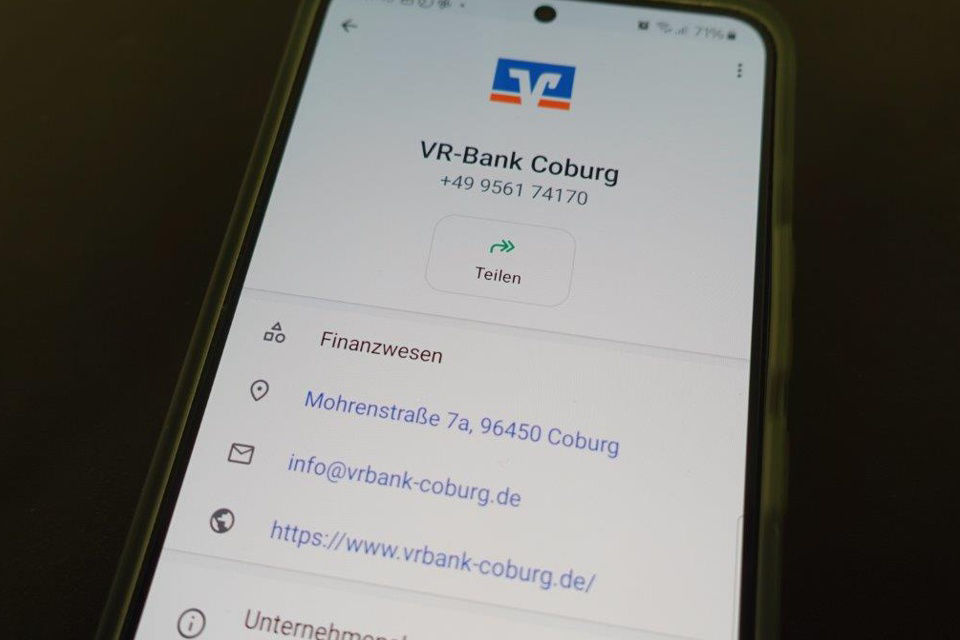 Smartphone zeigt das WhatsApp-Profil der VR-Bank Coburg an