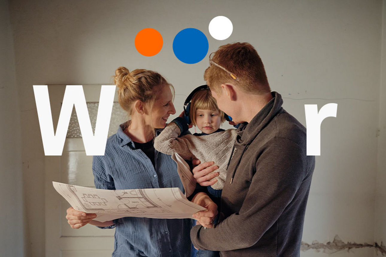 Eine Familie schaut sich freudig einen Bauplan an