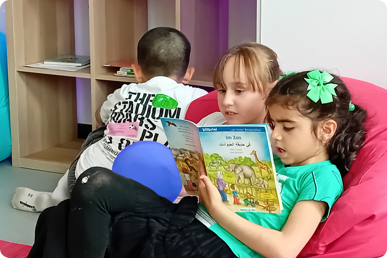 Kinder lesen gemeinsam ein Bilderbuch in einer gemütlichen Leseecke.