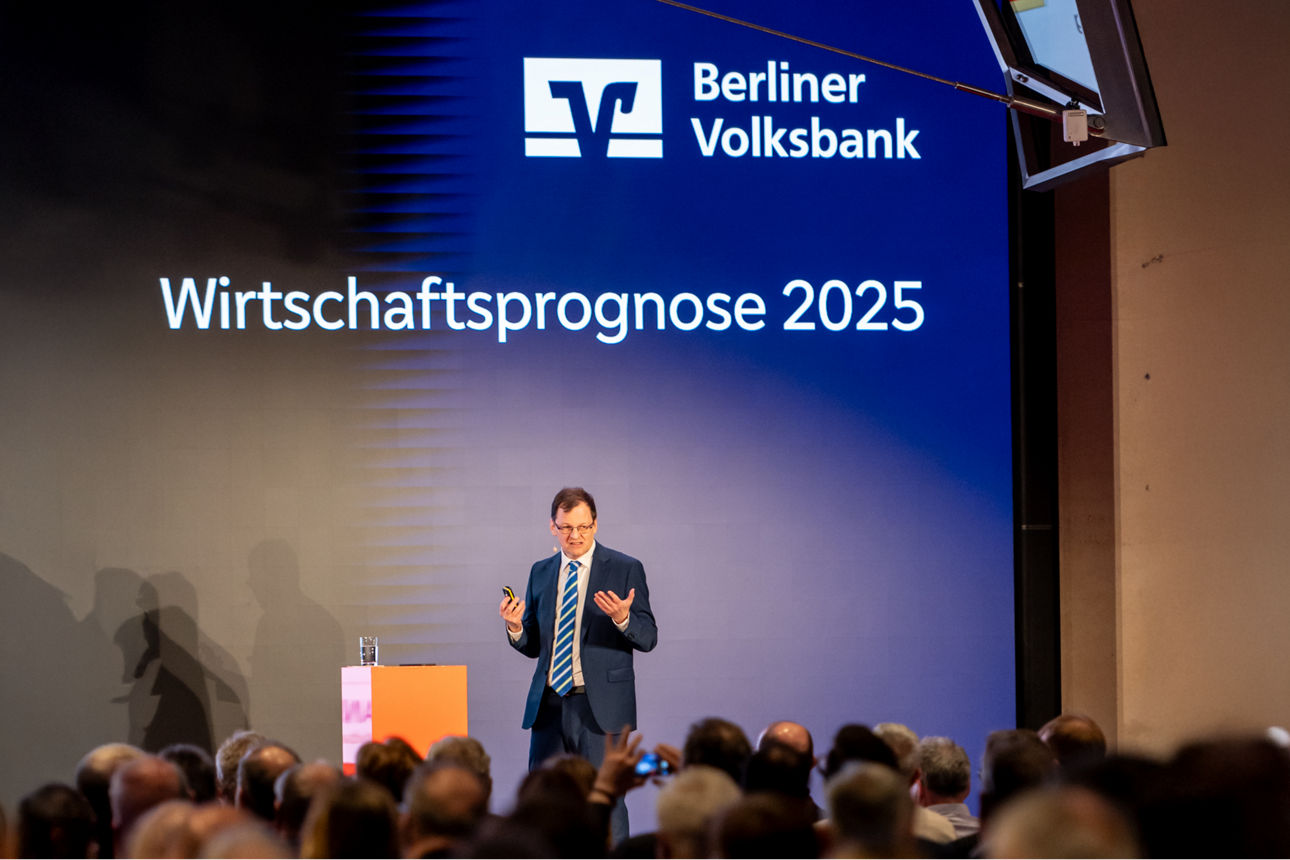 2025: Wirtschaftsprognose – Herausforderungen und Chancen für Unternehmen Dr. Michael Holstein steht auf einer Bühne und referiert vor Publikum