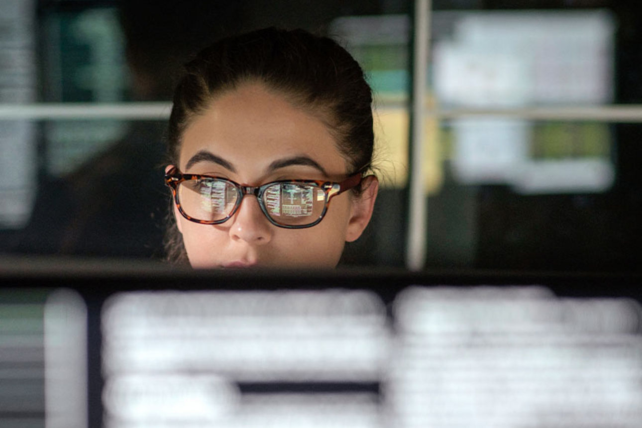 Junge frau mit Brille sitzt vor einem Bildschirm