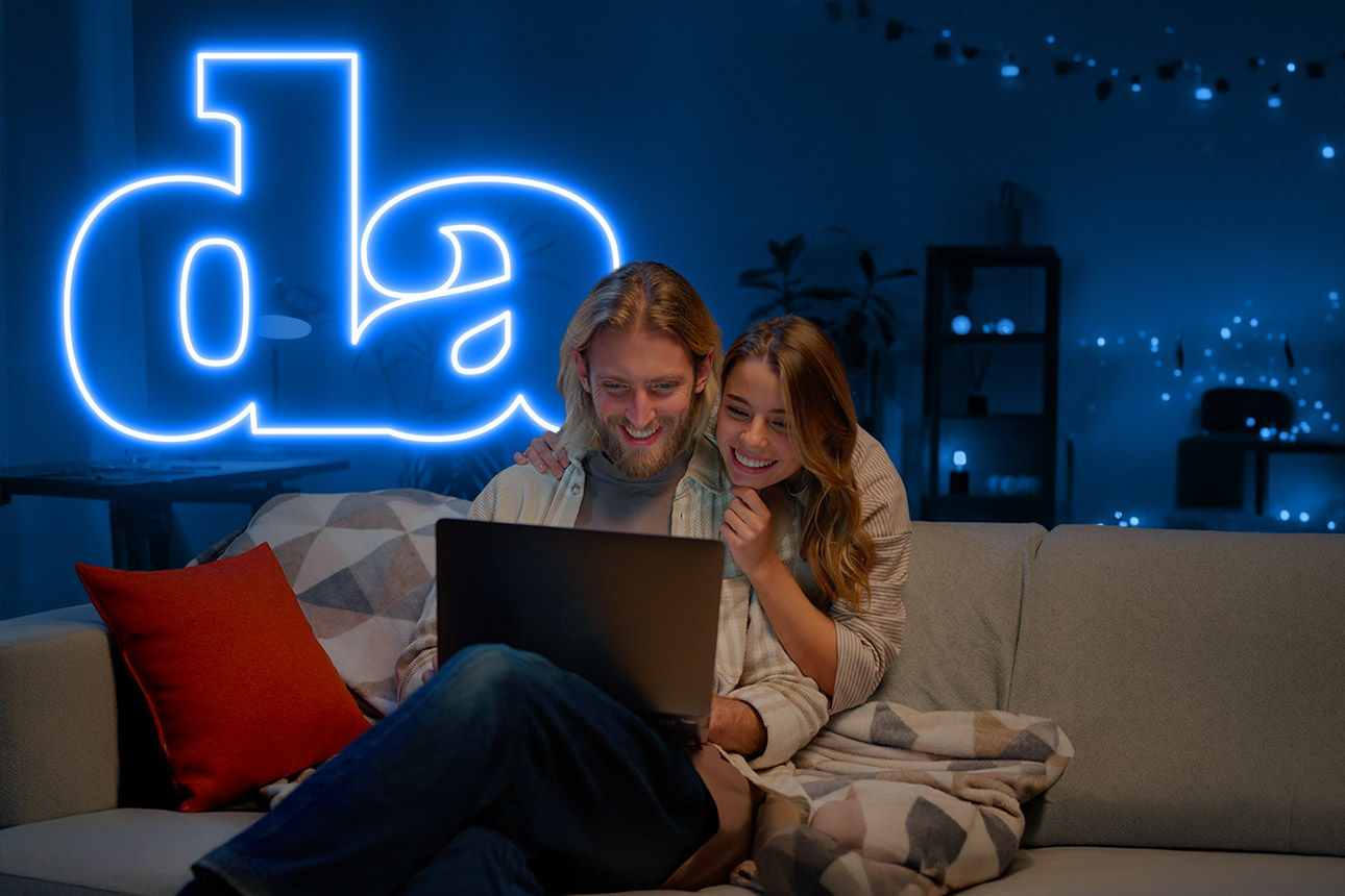 Junges Paar sitzt auf der Couch und schaut auf einen Laptop