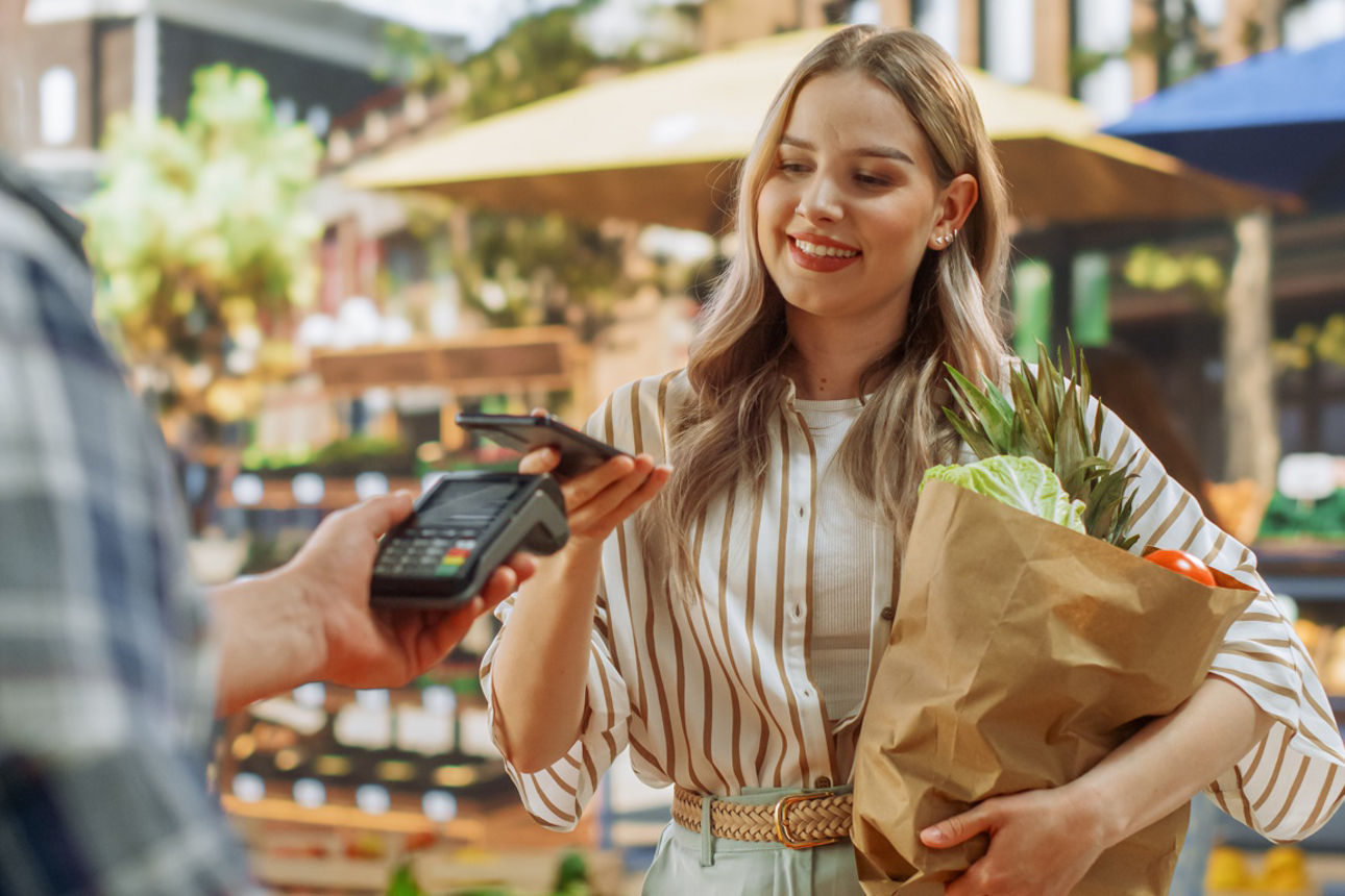 Eine Frau mit VR Banking App auf dem Smartphone trinkt einen Cappuccino
