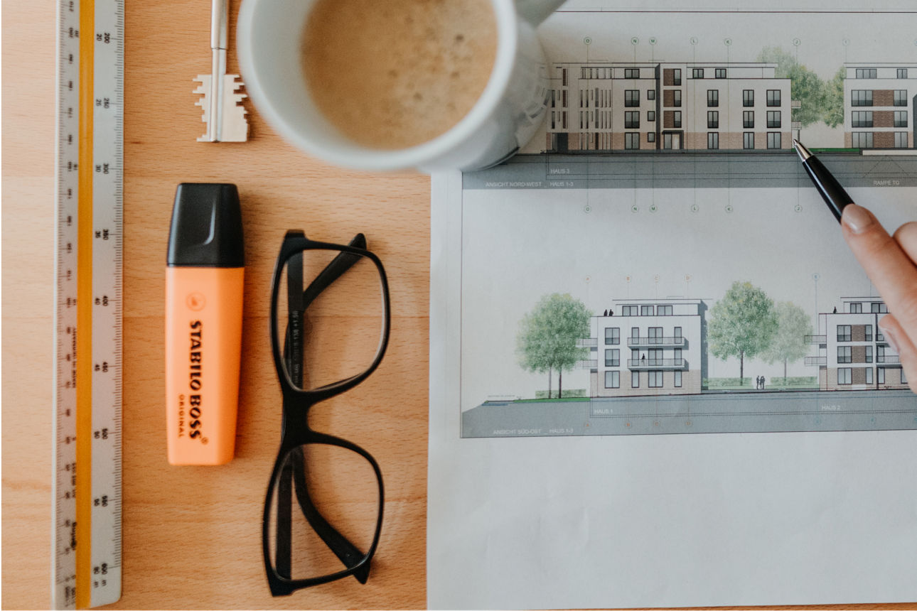 Eine Person skizziert auf Papier, während eine Kaffeetasse daneben steht