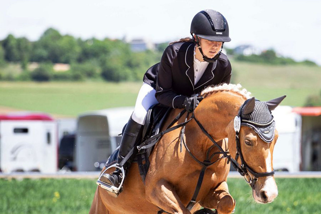 Junge Frau mit Pferd springt über ein Hindernis