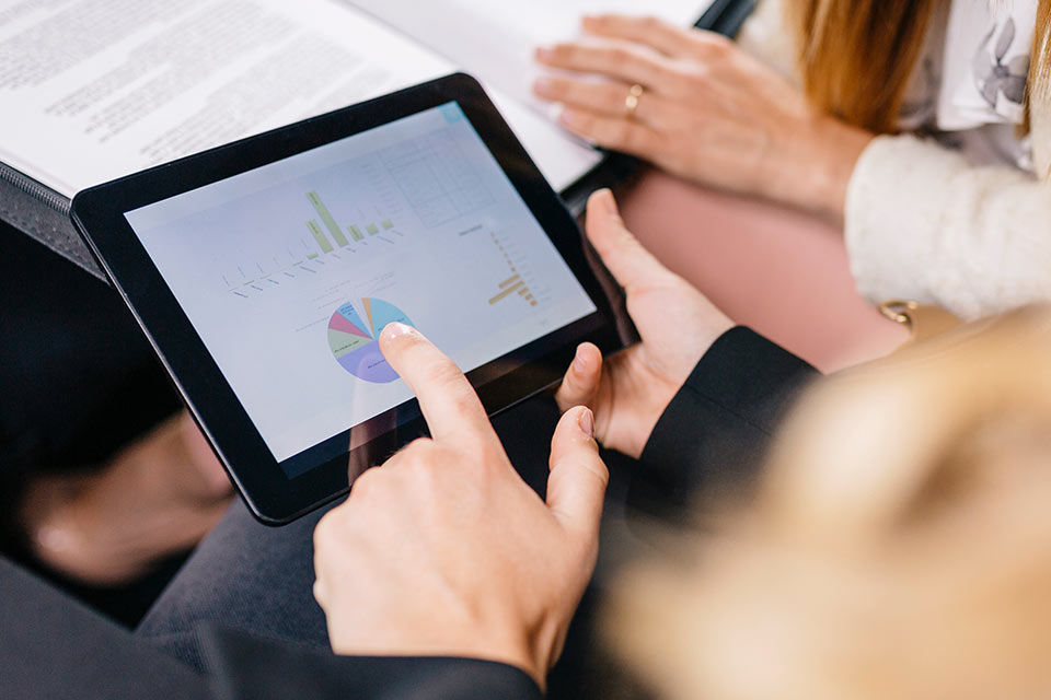 Ein Tablet mit Statistiken in einem Paar Hände