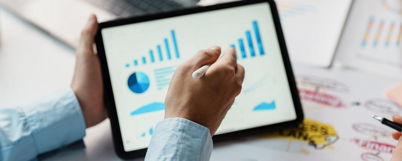 Ein Tablet mit Statistiken in einem Paar Hände