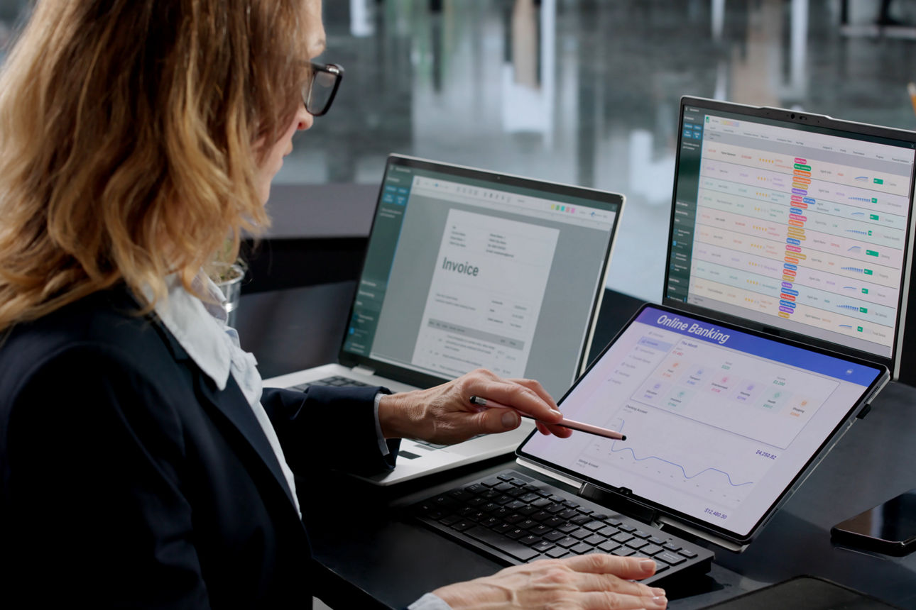 Frau arbeitet an Laptop und Tablet mit Rechnungen und Online-Banking-Daten