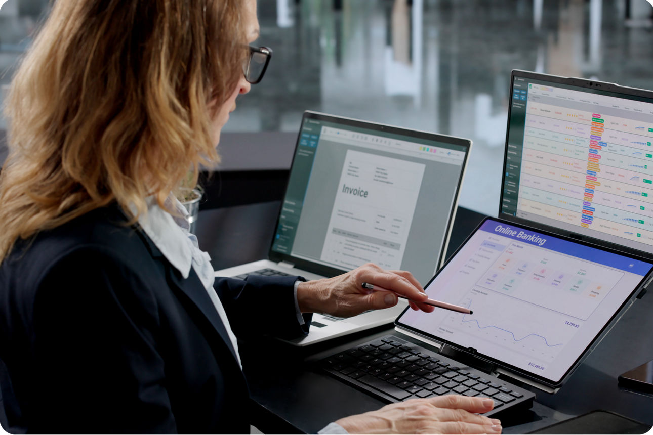 Frau arbeitet an Laptop und Tablet mit Rechnungen und Online-Banking-Daten