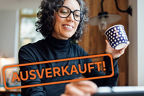 Frau mit Kaffeetasse arbeitet an einem Tablet