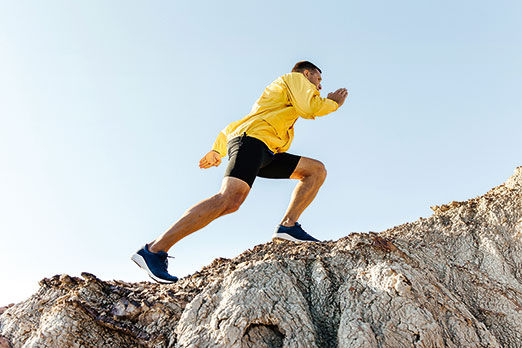 man climb uphill mountain in yellow jacket background sky