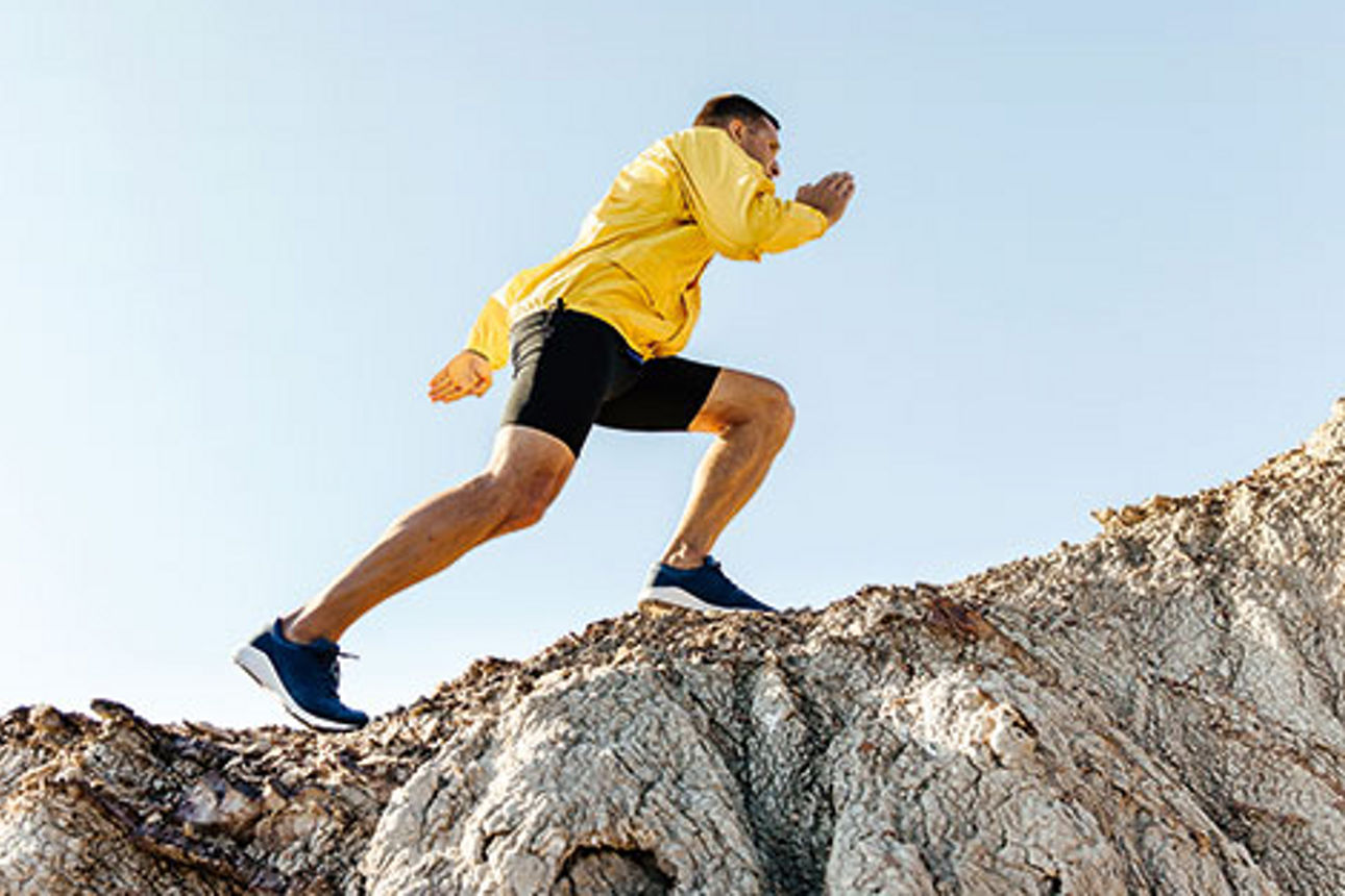 man climb uphill mountain in yellow jacket background sky