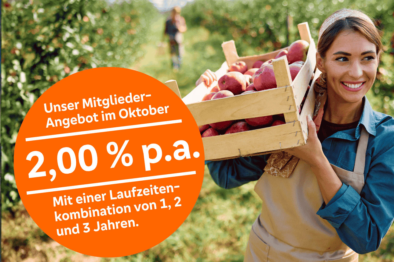 Lächelnde Frau trägt Kiste mit Äpfeln auf ihrer rechten Schulter.