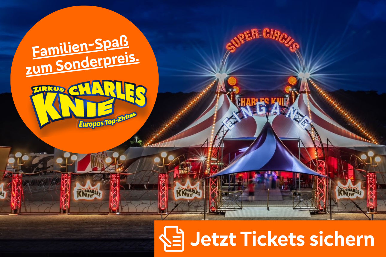 Beleuchtetes Zirkuszelt von Charles Knie bei Nacht, mit orangefarbigem Kreis für Familienspaß‑Sonderpreis.