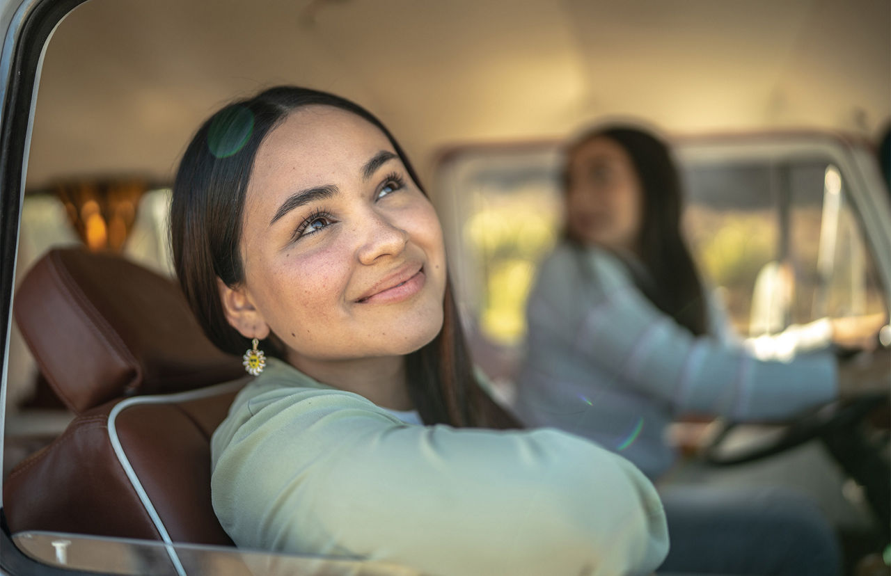 Junge Frau, die auf einem Roadtrip im Retro-Minivan wegschaut