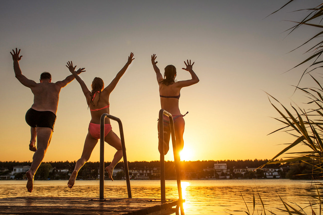 Drei junge Erwachsene springen in einen See