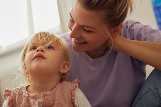 Kleines Mädchen auf dem Schoß seiner Mutter