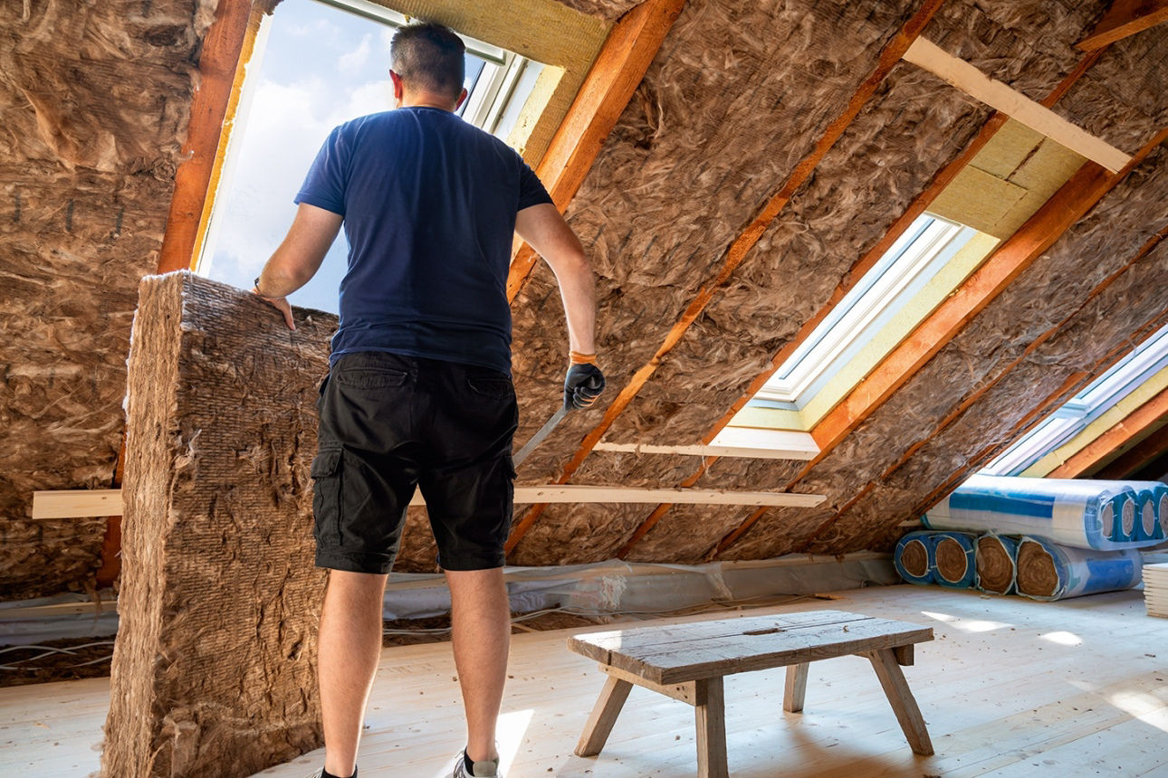 Handwerker bringt im Dachgeschoss Wärmedämmung an.