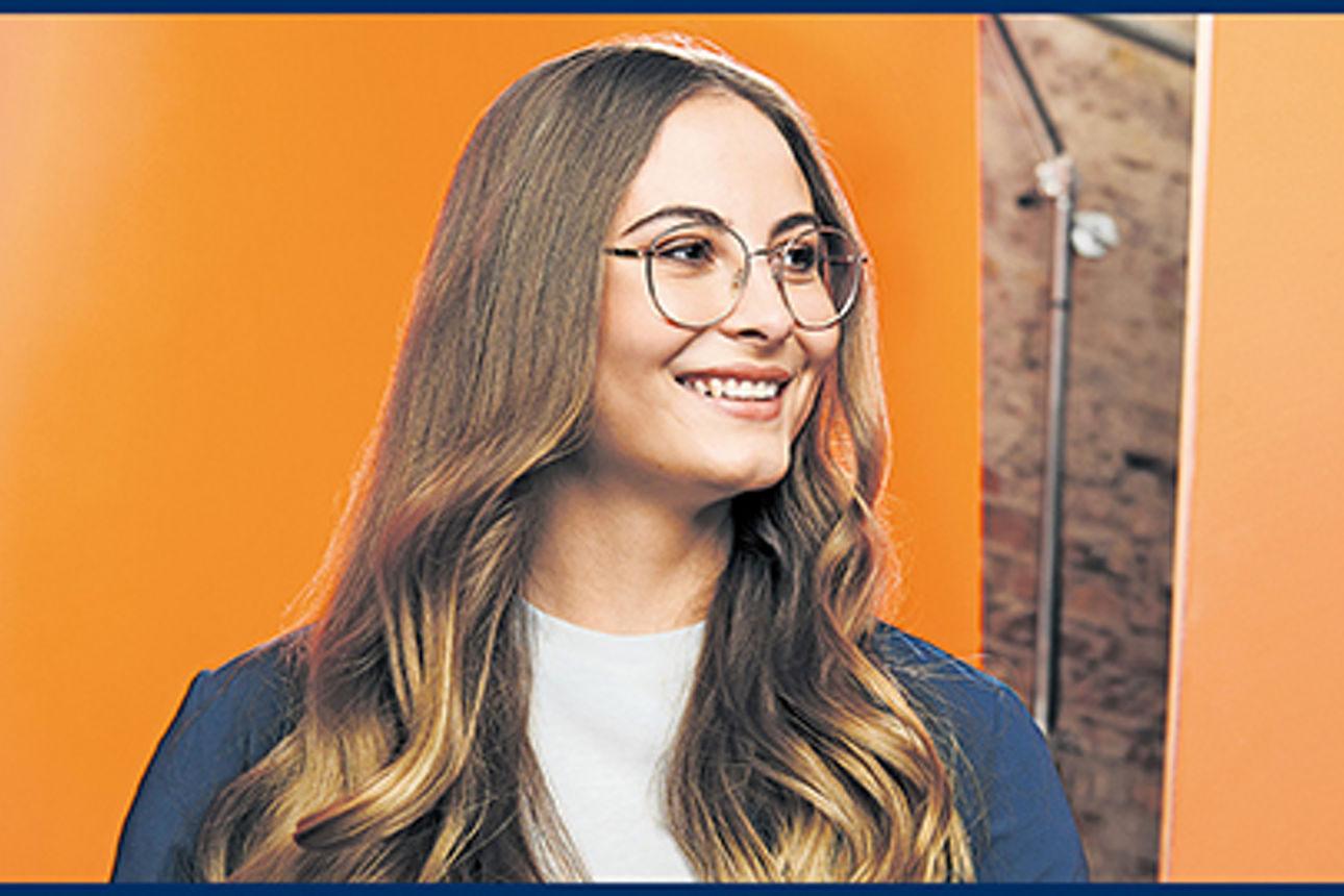 Eine junge Frau mit Satinhaaren und Brille lächelt